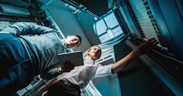 Two IT security professionals reviewing data logs